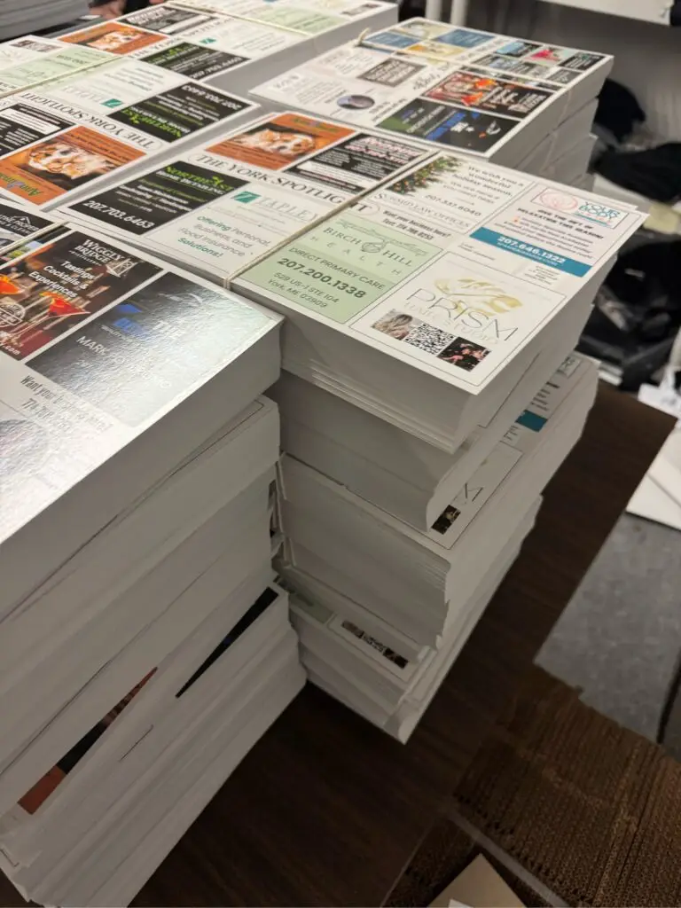 Stacks of 9x12 EDDM postcards featuring multiple small business ads, ready for mailing to local neighborhoods.