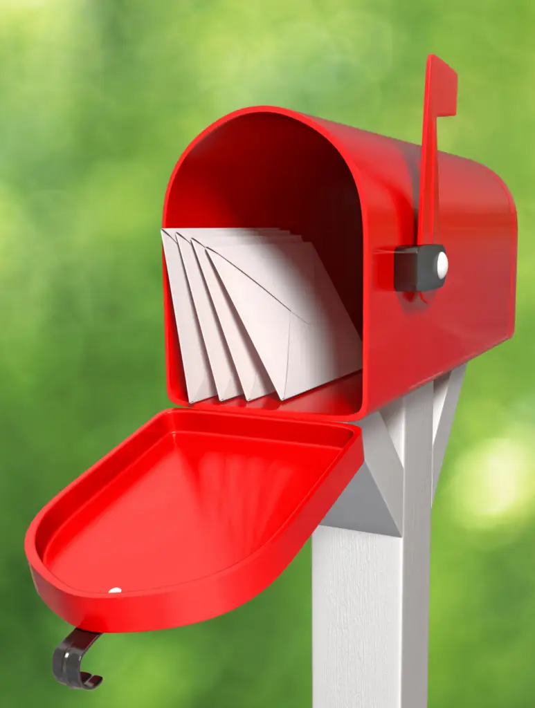 Sinlge traditional red residential mailbox in a neighborhood, filled with envelopes, representing direct mail delivery to local homes.