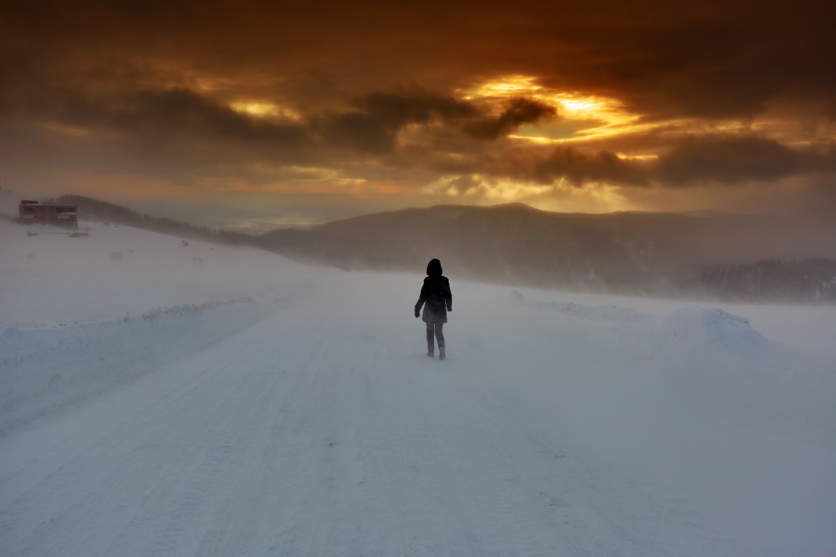 Person walking alone on a snow-covered road, representing the challenge of doing marketing without systems or support