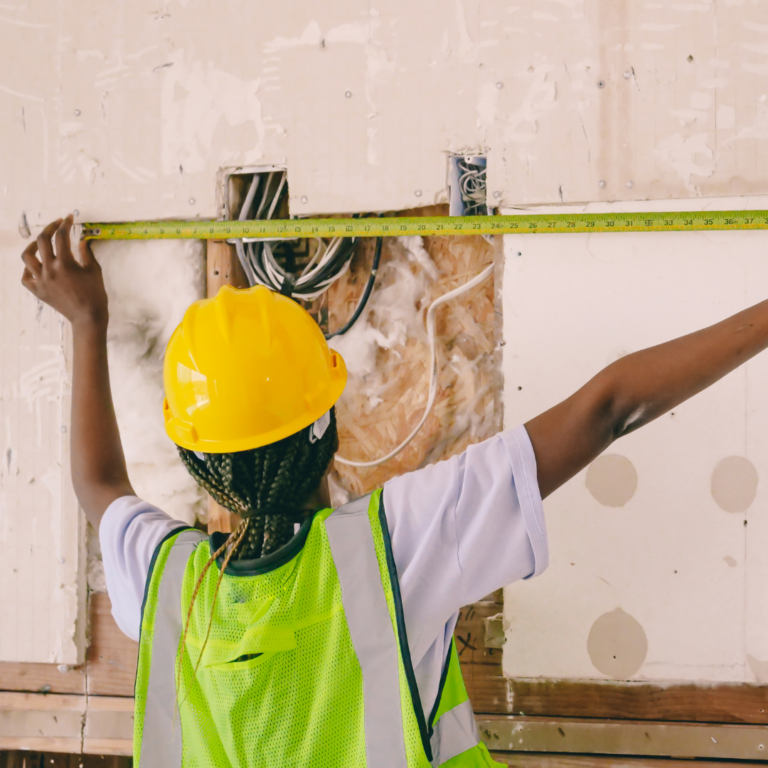 Contractor measuring wall on job site — focused on the work, not the marketing