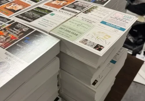 Stacks of 9x12 EDDM postcards featuring multiple small business ads, ready for mailing to local neighborhoods.